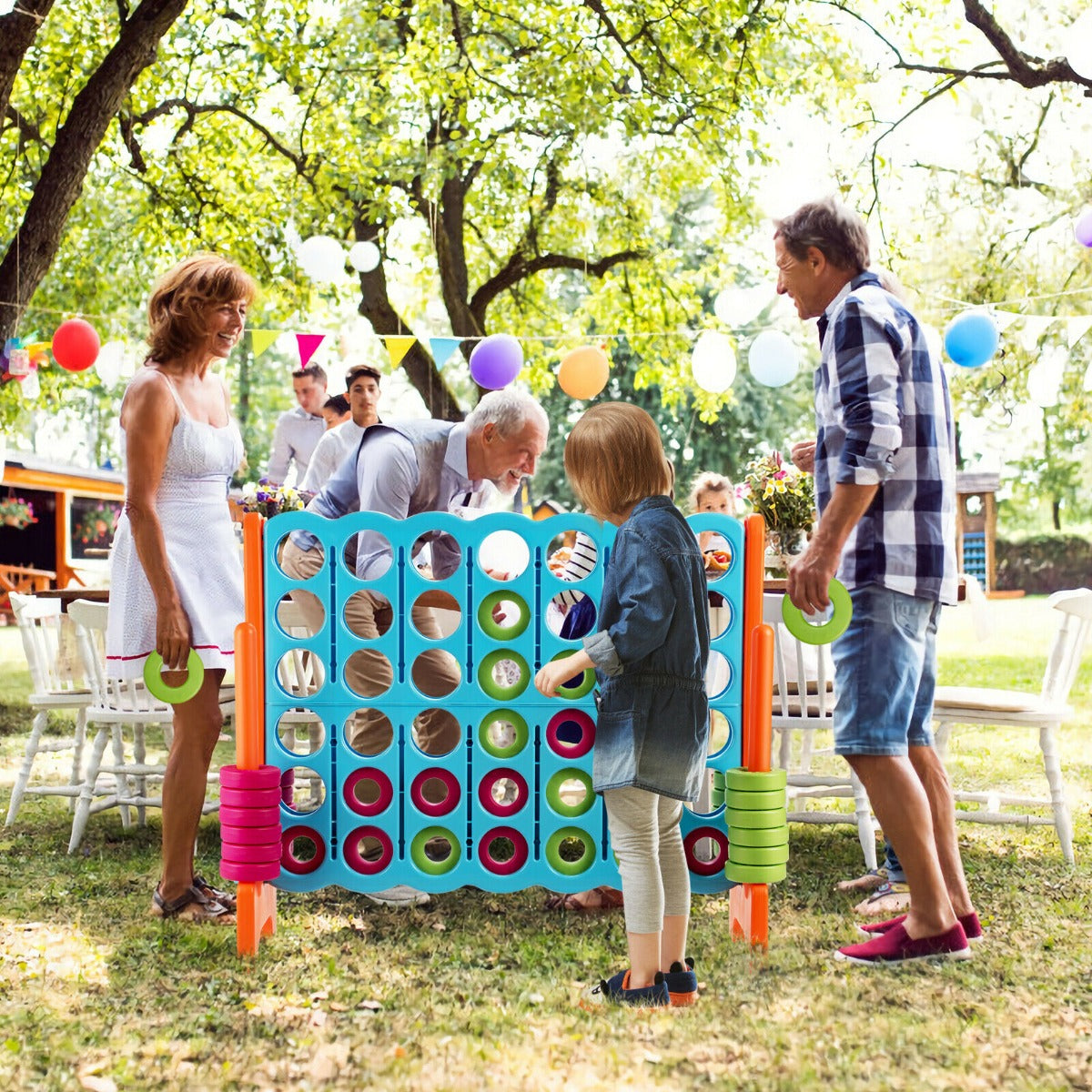 A family playing the giant four in a row lawn game at a garden party