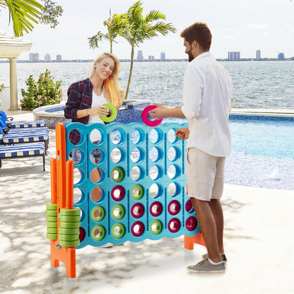 A couple playing the giant four in a row lawn game by a swimming pool