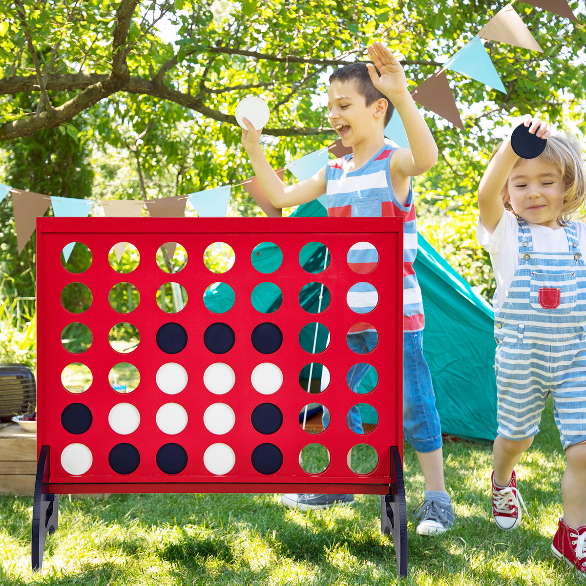 Children play the giant four-in-a-row game in a garden setting