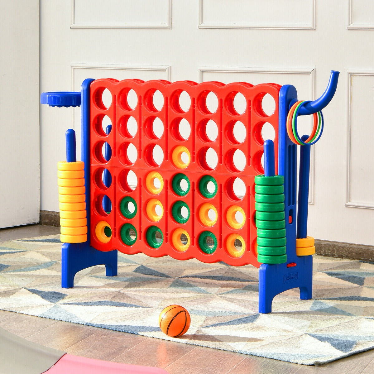 The lawn game stands on a patterned rug in a room with a small basketball on the floor
