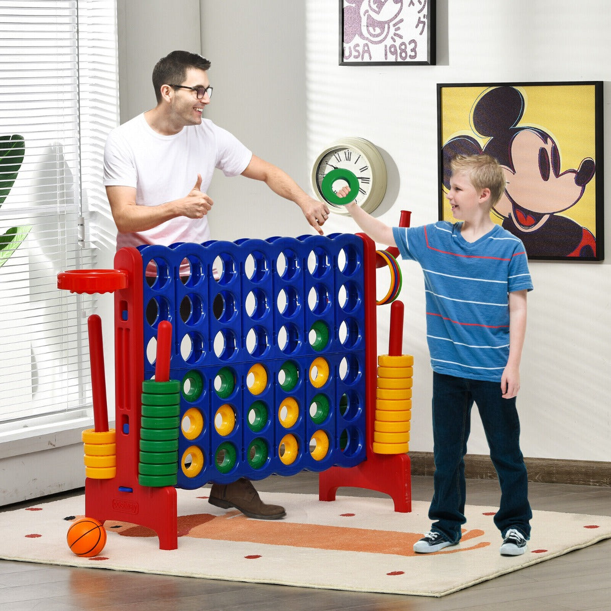 A man and a boy playing with the lawn game on a rug in a bright living room