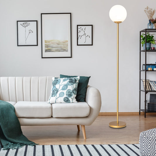 The golden floor lamp with a white globe shade is placed next to a sofa in a living room