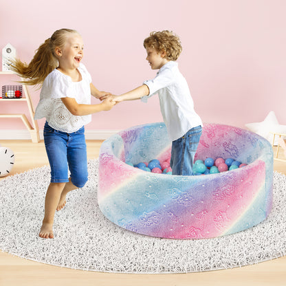 Two children hold hands and dance around the edge of the soft round ball pool