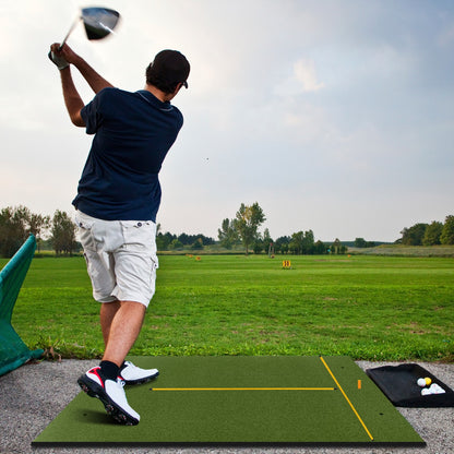 Man practicing golf swings on a golf hitting mat at an outdoor driving range