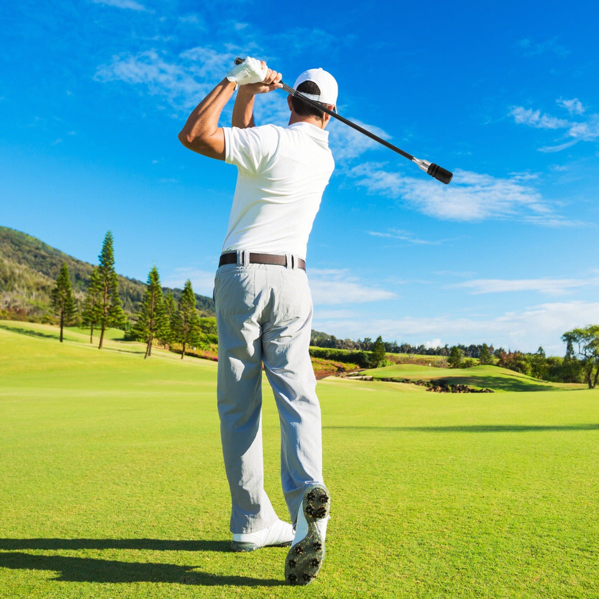 A golfer practicing his swing on a golf course with the golf swing trainer