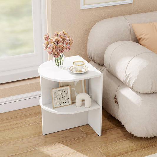 The white two-tier half moon side table placed next to a sofa, styled with books and a vase