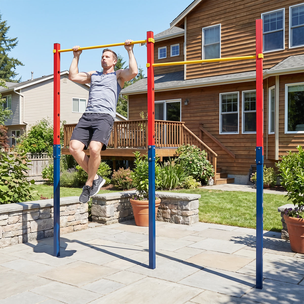 A man doing pull ups on the red and blue pull up bar station in a garden