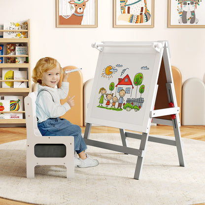 A young boy draws on the chalkboard of the art easel while sitting on the included chair