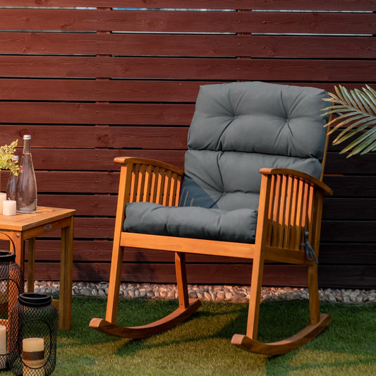 The seat pad placed on a wooden rocking chair on a patio with a dark fence background