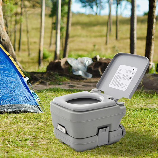 The portable toilet placed on grass next to a blue tent at a campsite