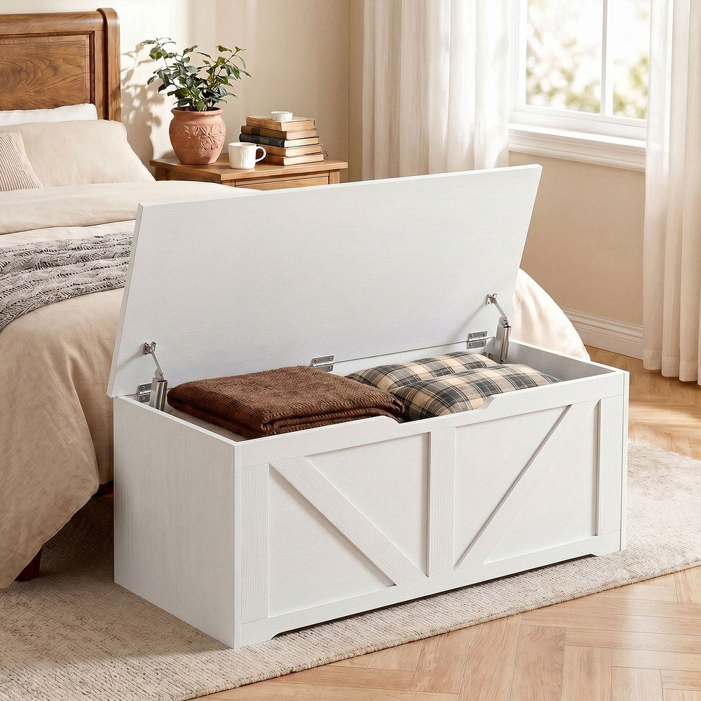 White wooden storage chest with the lid open, placed at the foot of a bed