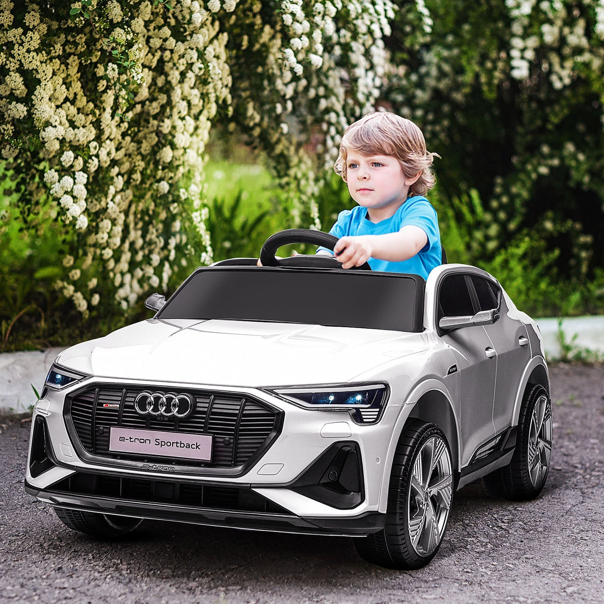 A young boy drives the white kids electric ride-on car outdoors