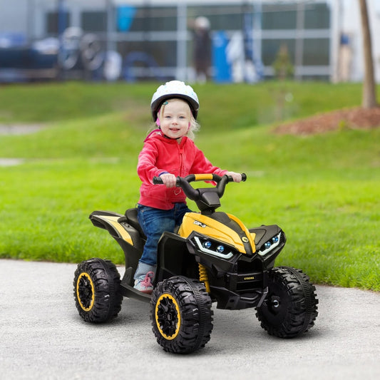 A happy toddler wearing a white helmet rides the yellow electric quad bike outdoors