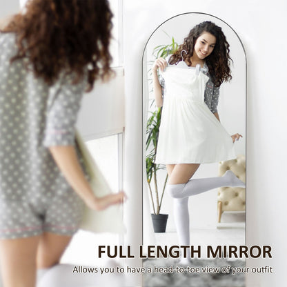 A woman holding a dress in front of the arched full length mirror