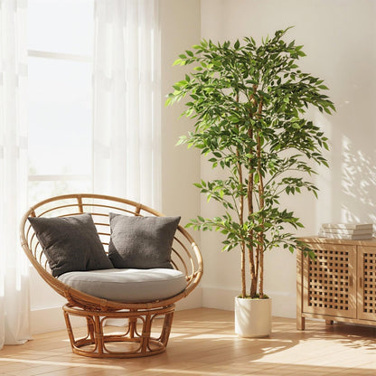 The artificial ficus tree placed in a bright room next to a rattan chair and a wooden cabinet
