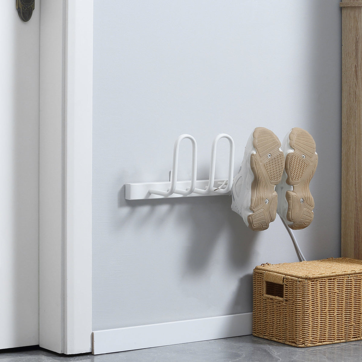 The electric shoe dryer mounted on a wall with a pair of trainers hanging on the drying arms