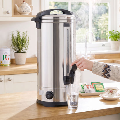 The catering urn dispensing hot water into a glass, with tea bags on a saucer nearby