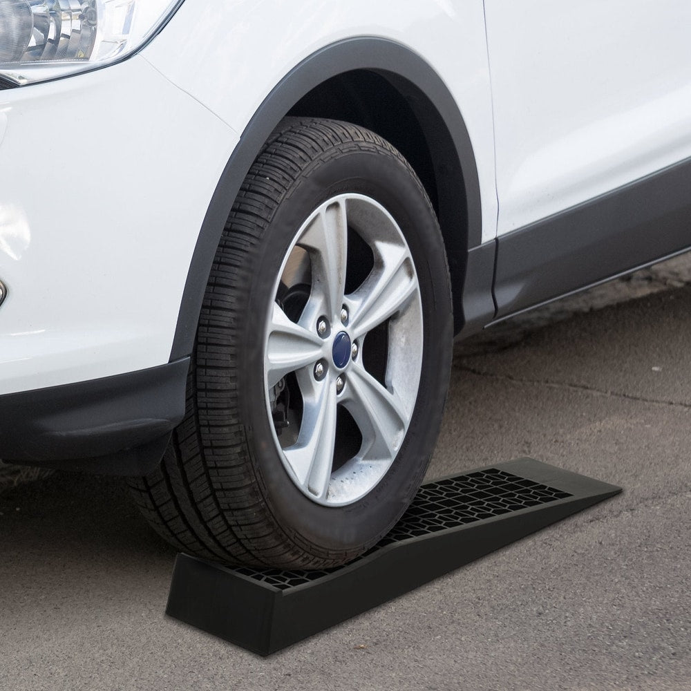 The car ramps positioned under a vehicle tyre on a paved driveway