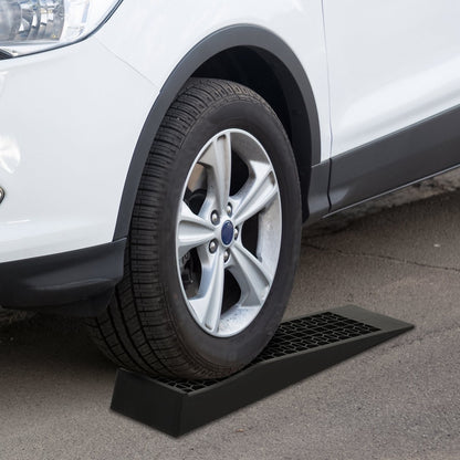 The car ramps positioned under a vehicle tyre on a paved driveway