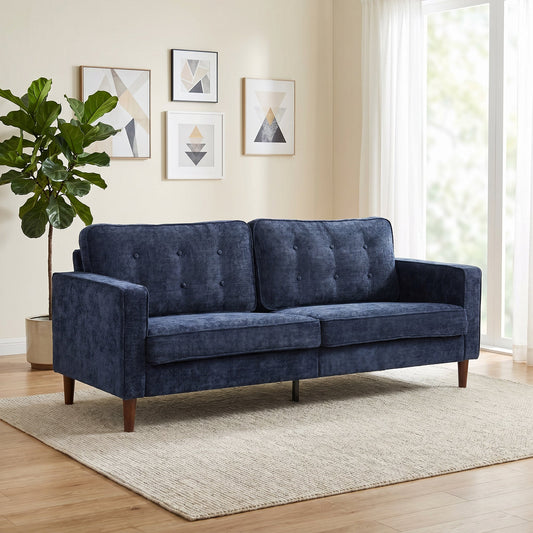 Dark blue three seater sofa with button tufting in a bright living room setting
