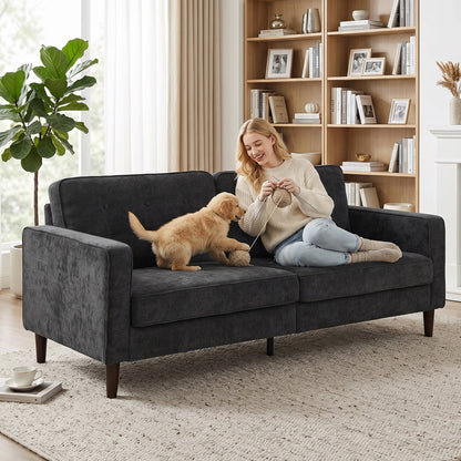 A woman and a puppy on the dark grey upholstered sofa in a cosy room