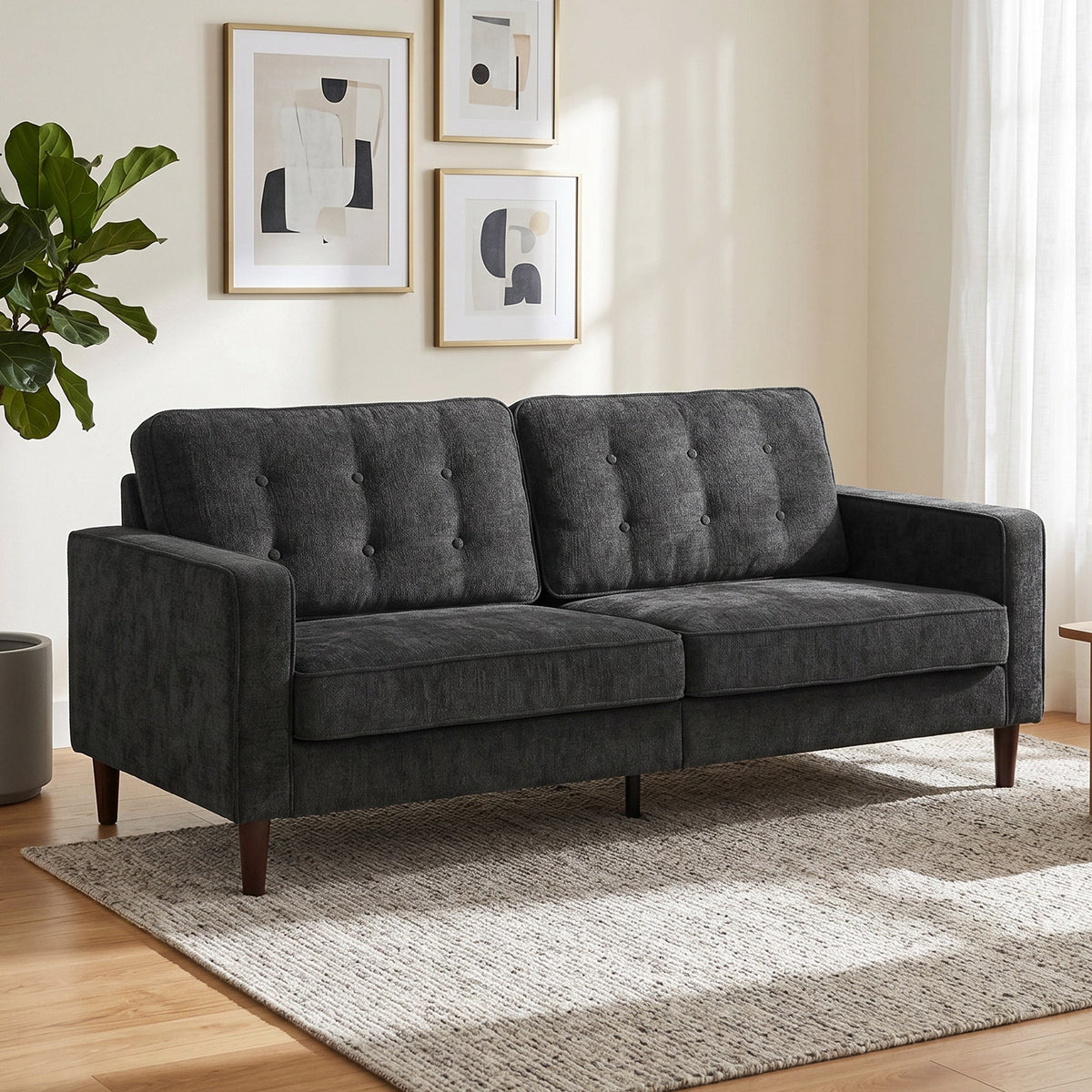 Dark grey upholstered sofa with button tufting and wooden legs in a living room setting