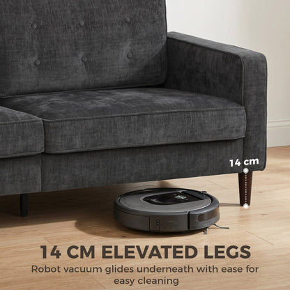Robot vacuum cleaner cleaning under the elevated legs of the dark grey sofa