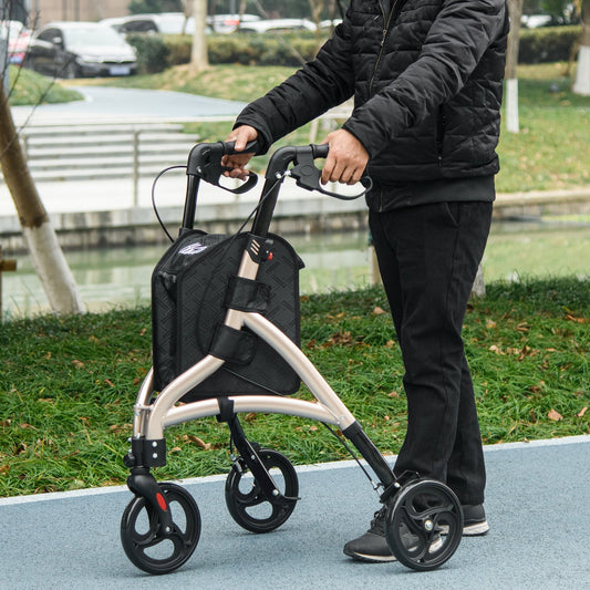 A person using the gold tone three wheel rollator outdoors on a paved path