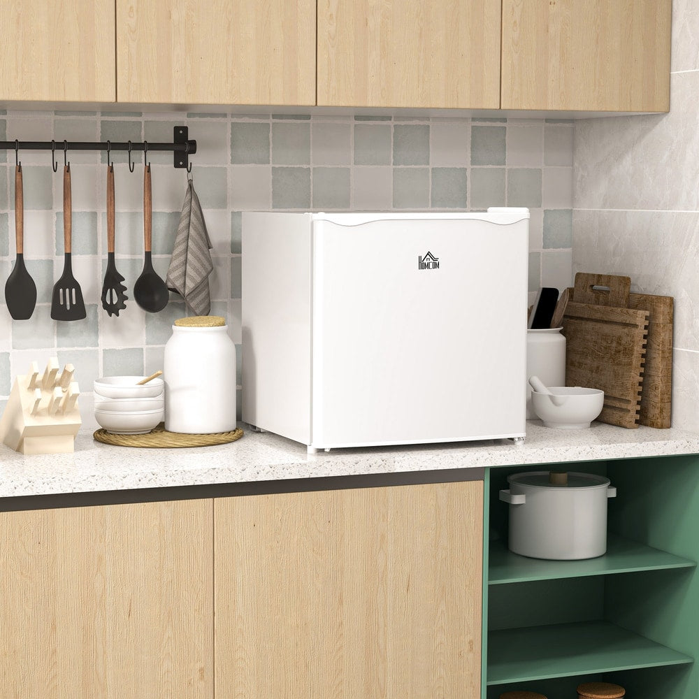 The white mini freezer sits on a kitchen counter next to bowls and utensils