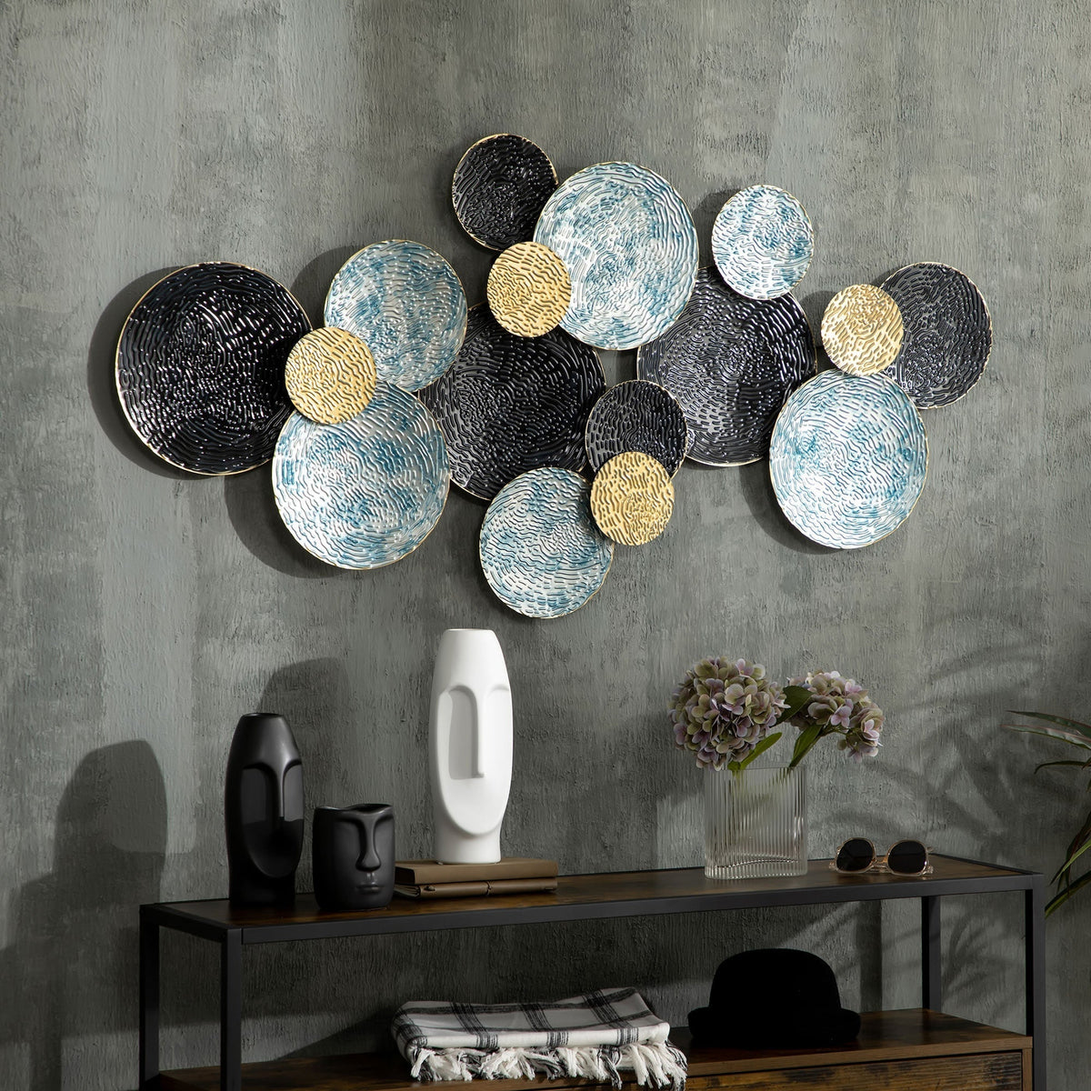 The metal wall art is displayed on a grey wall above a console table with decorative items