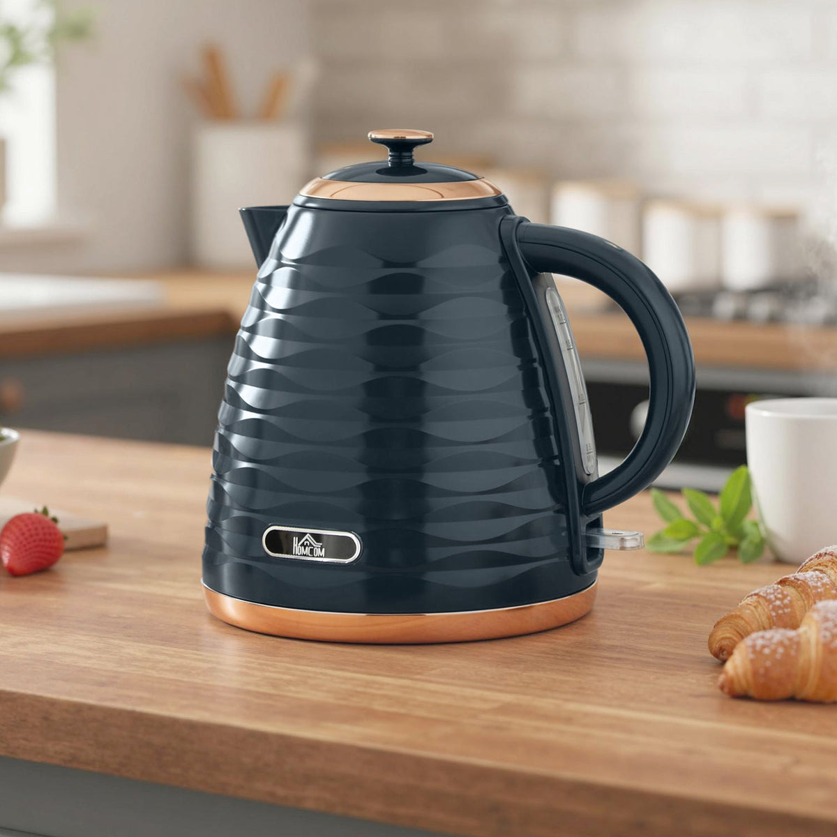 The honeycomb kettle sitting on a wooden kitchen counter next to a strawberry and croissants