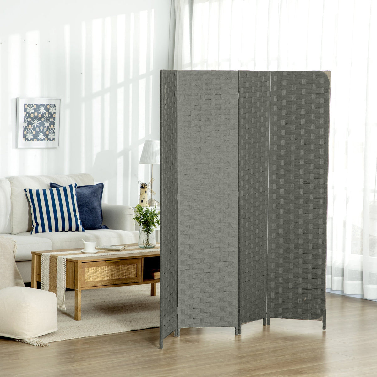 The grey four-panel room divider set up in a living room behind a sofa