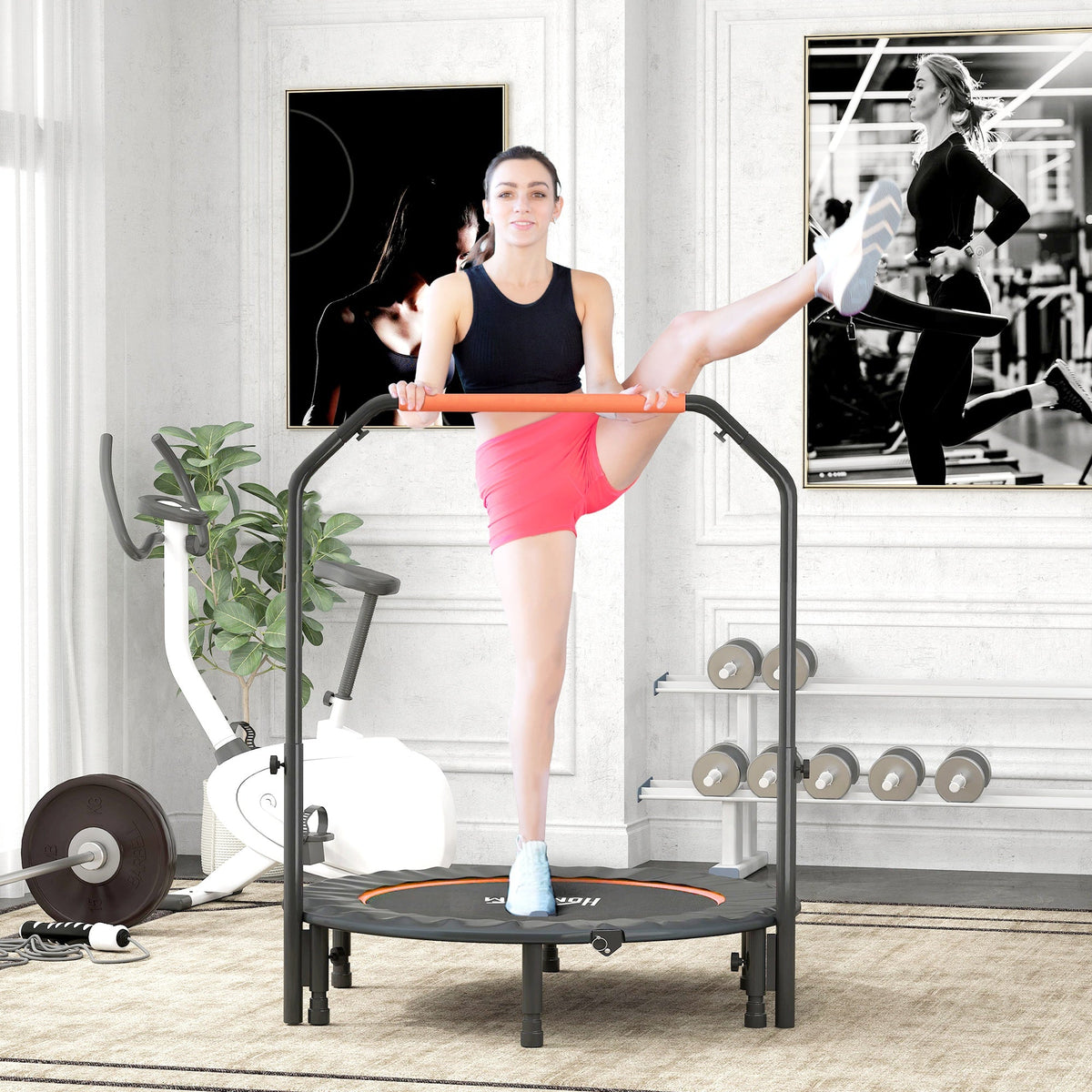 The orange and black fitness trampoline is used by a woman in a home gym setting