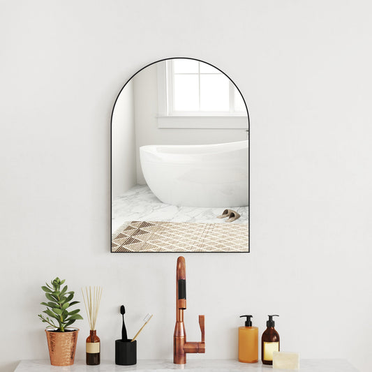 The arched bathroom mirror hanging above a sink in a modern bathroom setting