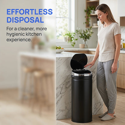 A woman using the black automatic sensor bin in a kitchen, demonstrating effortless disposal