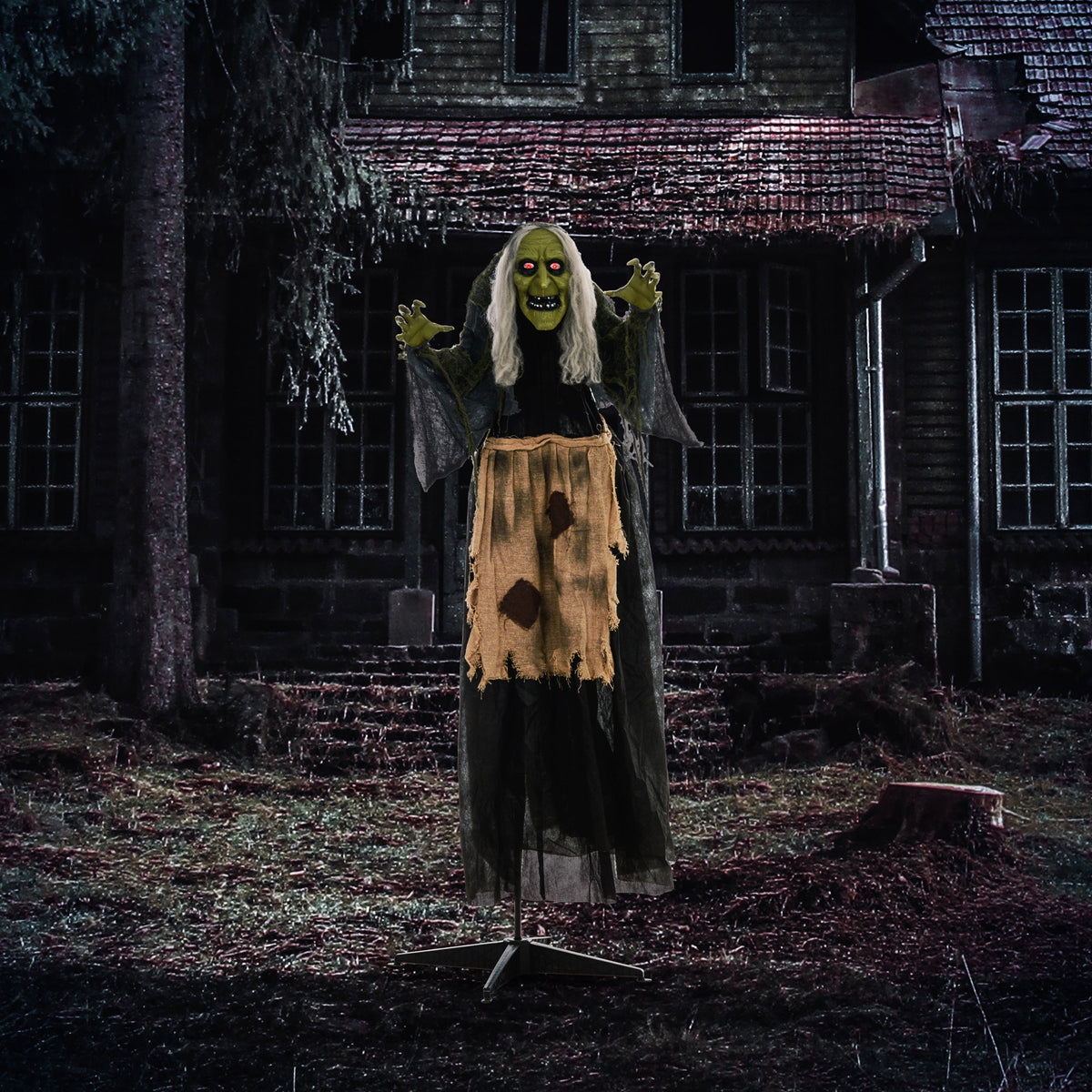 The hunchback witch Halloween animatronic standing outside a spooky house