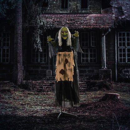 The hunchback witch Halloween animatronic standing outside a spooky house