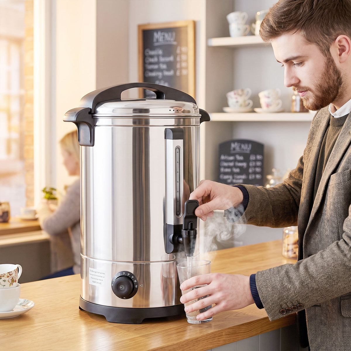 A man using the hot water boiler to fill a glass in a cafe or break room environment