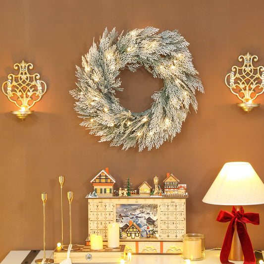 Flocked prelit Christmas wreath hanging above a mantelpiece with festive decorations