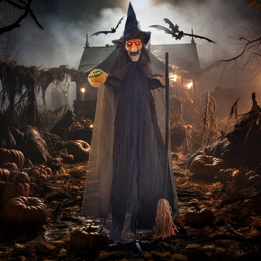 The Halloween witch animatronic in a spooky outdoor setting with pumpkins and a house