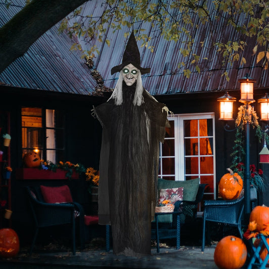 The hanging witch prop is displayed outdoors on a porch at night