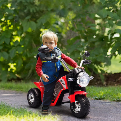 A young boy rides the red kids electric motorbike toy outdoors on a paved path