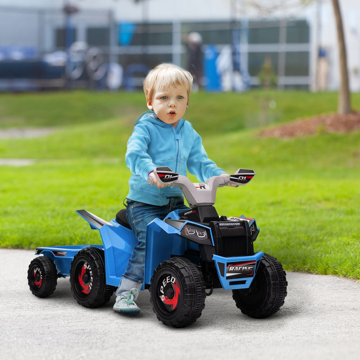 A young child rides the blue kids electric quad bike with trailer on a paved path