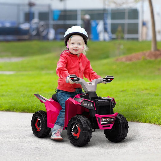 A happy toddler wearing a helmet rides the pink quad bike toy outdoors