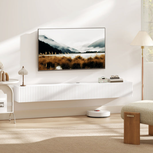 The white wall-mounted TV unit in a living room, holding a television and a lamp