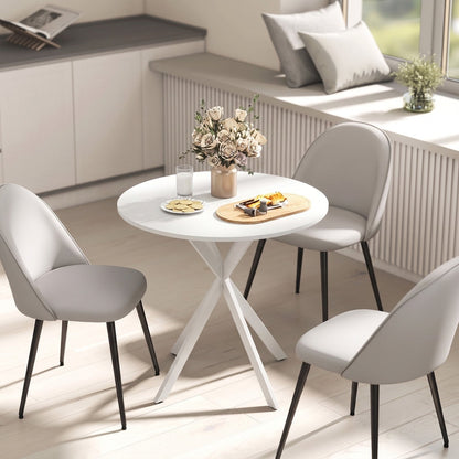 The round dining table in a bright kitchen setting with three chairs