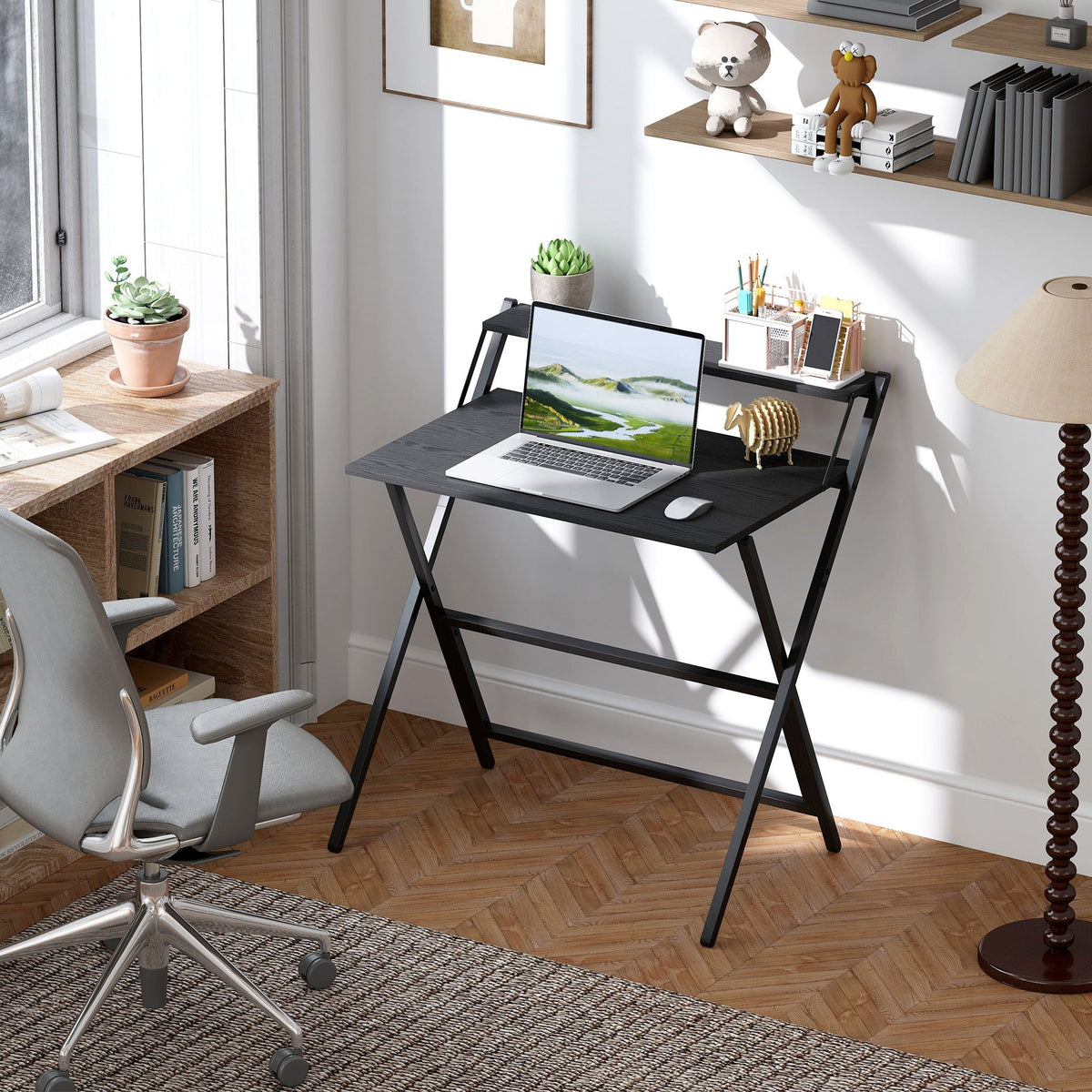 Black folding computer desk set up in a home office with a laptop and chair