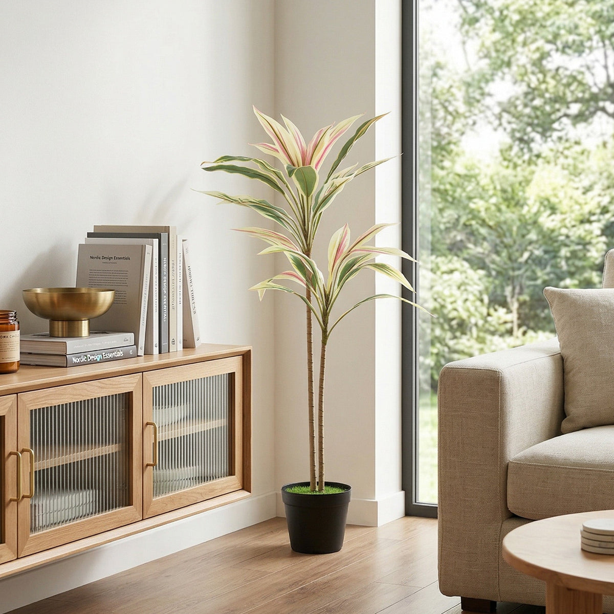 Artificial cordyline tree in a black pot standing in a modern living room next to a sofa