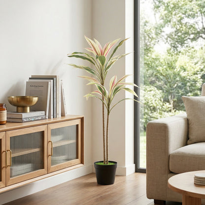 Artificial cordyline tree in a black pot standing in a modern living room next to a sofa