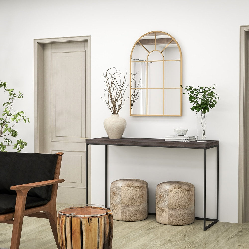 Gold tone arched grid mirror above a dark wood console table with decorative items